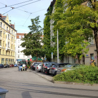 Blick auf das „Gleisdreieck“ am Beginn der Kirchenstraße, Bäume und Fassadenbegrünung bis in den vierten Stock