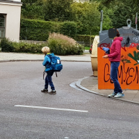 Schulkind tastet sich hinter den Containern – bereits auf der Fahrbahn – vor, um die Spicherenstraße zu überqueren