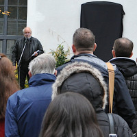 Hermann Wilhelm (links im Hintergrund) spricht vor der noch verhüllten Gedenktafel für Josef Schülein am ehemaligen Brauhaus der „Unionsbrauerei“ Haidhausen am 9. Nov. 2018